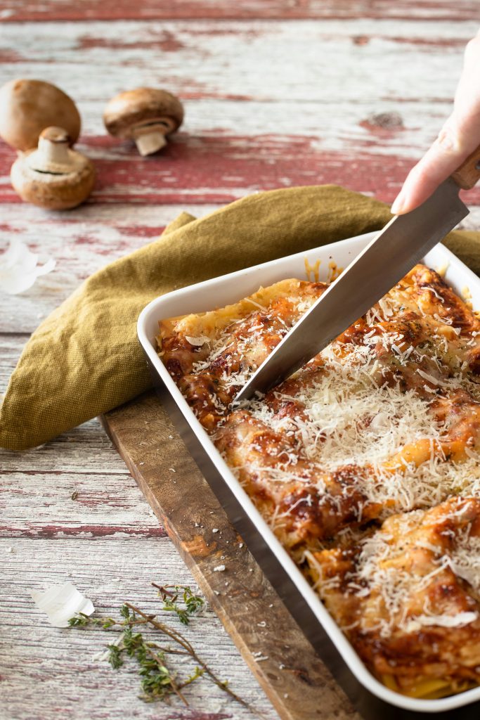 Appetizing homemade lasagna with cheese and herbs being sliced, ready to serve.